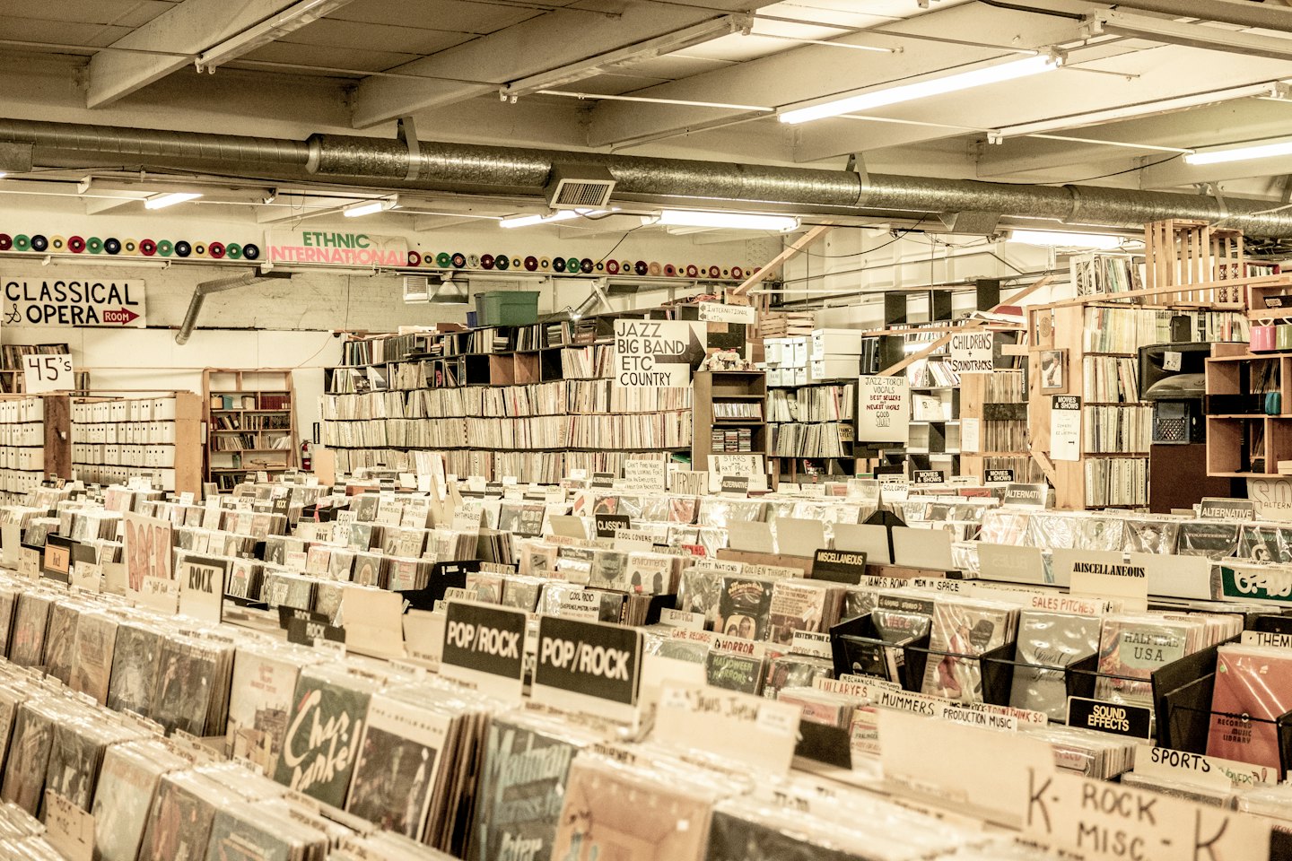 Rows of vinyl records and CDs in a brightly lit store.