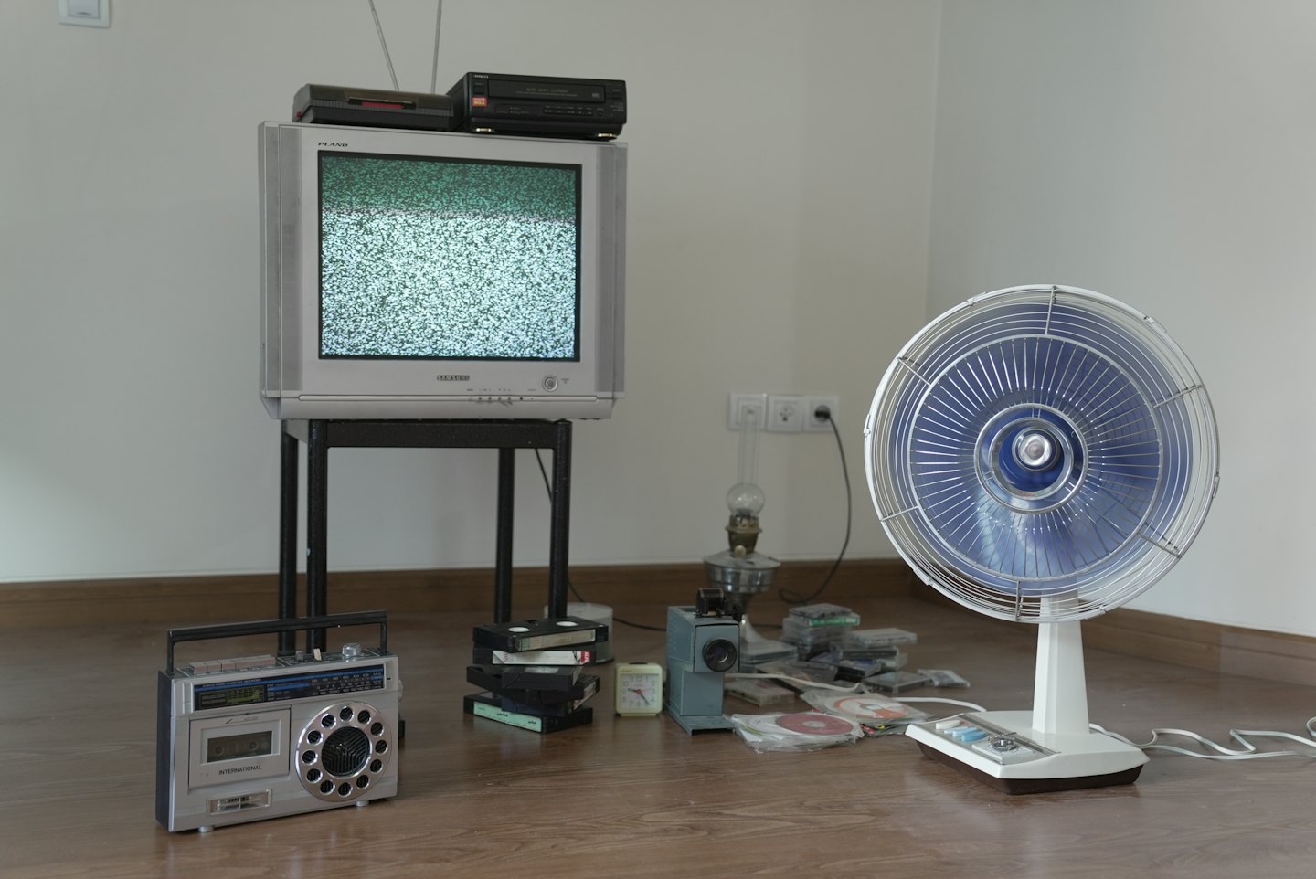 Vintage electronics and media arranged on a wooden floor.
